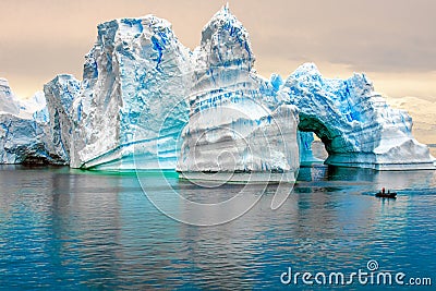 Iceberg in Antarctica, ice castle with Zodiac in front. Huge iceberg sculptured like fairytale castle Stock Photo