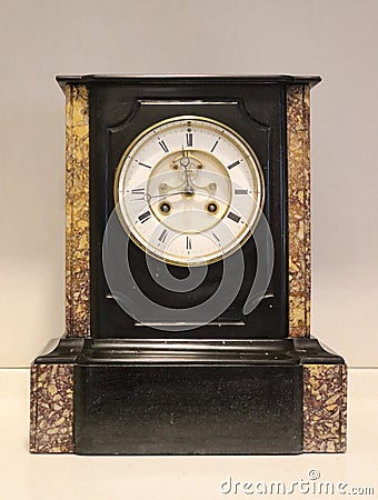 French antique black and brown marble clock with a white face. Stock Photo