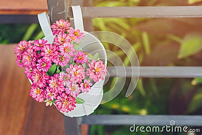 Beautiful artificial flowers in small pots hanging to decorate a railing walk for beauty on the pathway in public gardens. Stock Photo