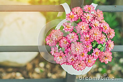 Beautiful artificial flowers in small pots hanging to decorate a railing walk for beauty on the pathway in public gardens. Stock Photo