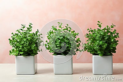 Beautiful artificial plants in flower pots on marble table against color background Stock Photo