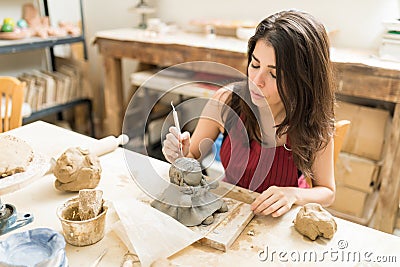 Beautiful Artisan Making Pottery Of Doll In Studio Stock Photo