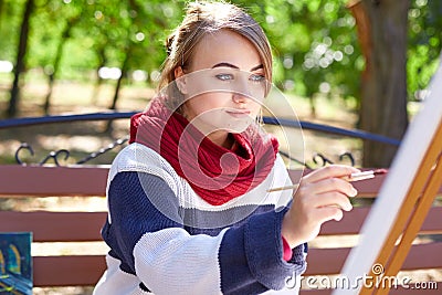 Beautiful artist draws a picture in a good mood outdoors. Stock Photo