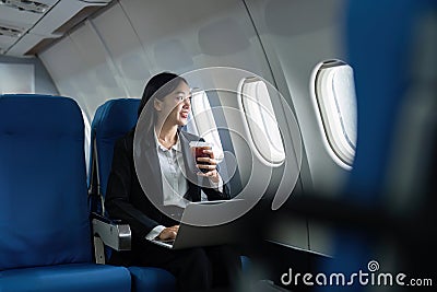 Beautiful Asian businesswoman working with laptop in aeroplane. working, travel, business concept Stock Photo