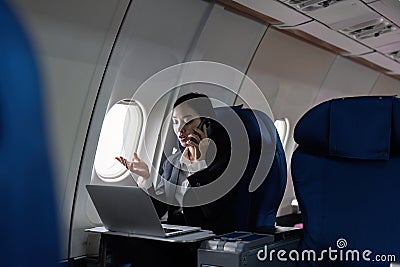 Beautiful Asian businesswoman working with laptop and mobile in aeroplane. working, travel, business concept Stock Photo