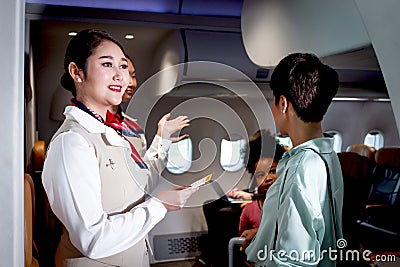 Beautiful Asian female air hostess standing at airplane entrance gate, flight attendant woman welcome and check passenger before Stock Photo