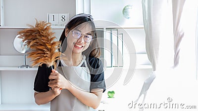 Beautiful Asian housewife wearing apron and cleaning gloves prepares to clean her house Stock Photo