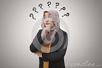 Beautiful Asian muslim business woman wearing hijab looking up and thinking with question mark, businesswoman confused of a Stock Photo
