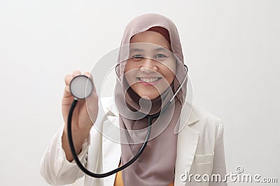 Beautiful Asian muslim female medical doctor wearing hijab want to make examination with stethoscope, smiling to camera Stock Photo