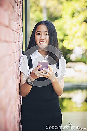 Beautiful asian teenager toothy smiling face using smarphone in Stock Photo