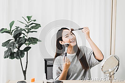 Beautiful asian woman applying and makeup on her face with brush,Beauty concept Stock Photo