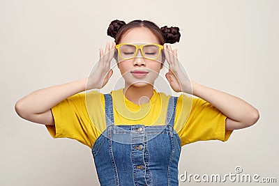 Beautiful Asian woman has two buns of hair wearing a jeans dungaree and adjusting glasses Stock Photo