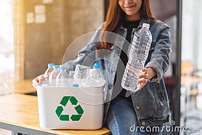 A beautiful woman holding and collecting recyclable garbage plastic bottles into a trash bin at home Stock Photo
