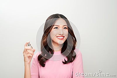 Beautiful asian woman holding a perfume bottle and applying it Stock Photo