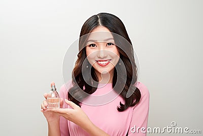 Beautiful asian woman holding a perfume bottle and applying it Stock Photo