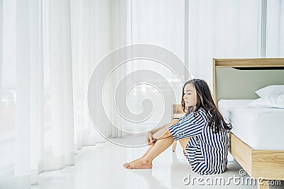 Beautiful asian woman sitting on the floor near bed feeling depressed stress in bedroom, Young woman suffers from insomnia Stock Photo