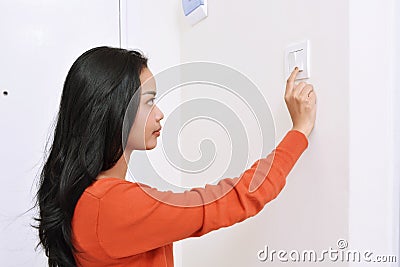 Beautiful asian woman turning off the light with wall switch Stock Photo