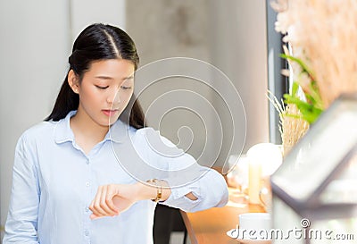 Beautiful asian young woman look at watch waiting for friend or someone. Stock Photo