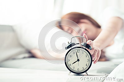 Beautiful asian young woman turn off alarm clock in morning, wake up for sleep with alarm clock Stock Photo