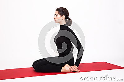 Beautiful athletic girl in a black suit doing yoga. Virasana asana hero pose. Isolated on white background. Stock Photo