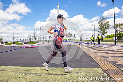 beautiful athletic girl runs at a city sports event, race, against the background of a new stadium Editorial Stock Photo