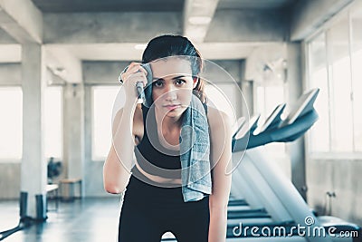 Beautiful Athletic Woman is Wiping Sweat With Towel in Gym, Portrait of Pretty girl in Sportswear is Exercising in Fitness Club. Stock Photo