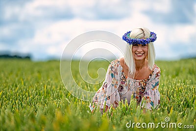 Beautiful, attractive, blonde woman with cornflower blue crown in the field of cereals Stock Photo