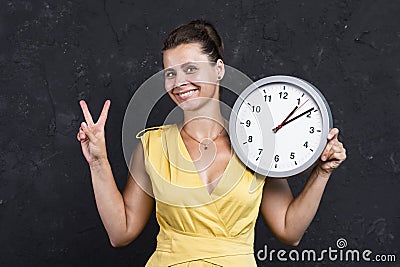 Beautiful attractive girl with a clock. A young woman is holding a round watch. Time concept Stock Photo