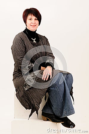 Beautiful attractive mature woman sitting in jeans Stock Photo