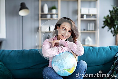 Beautiful attractive woman on couch holding globe and dreaming vacation Stock Photo