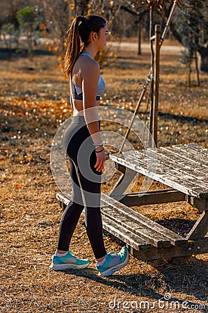 Beautiful attractive young toned runner, dressed in tights and a top, with long hair tied in a ponytail, stretching her calves Stock Photo