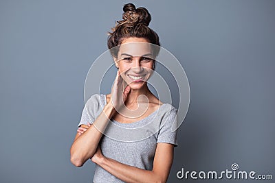 Beautiful authentic joyful woman with bun hair and natural smile on a gray background Stock Photo