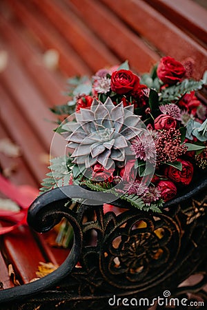 Beautiful autumn bouquet with red flowers and succulents on a bench outside Stock Photo