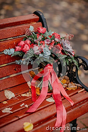 Beautiful autumn bouquet with red flowers and succulents on a bench outside Stock Photo