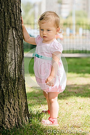 Beautiful baby girl touching a tree Stock Photo