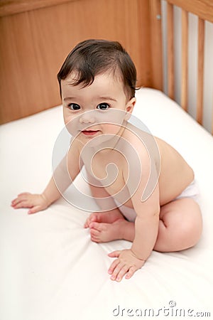 Beautiful baby sitting in cot Stock Photo