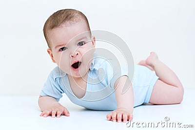 Horizontal studio image of cute yawning baby wearing blue bodysuit on white wall Stock Photo