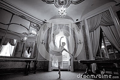Beautiful ballerina dancing in a luxurious hall with a chandelier and mirrors Stock Photo