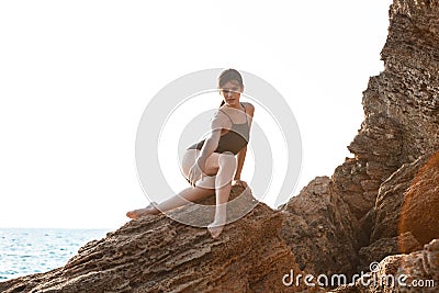 Beautiful ballerina dancing, posing on rock at beach, sea background. Stock Photo