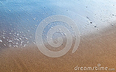 Beautiful beach sand background. Half dried and half wet with the soft sea waves. Stock Photo