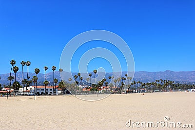palm trees line the beach in front of mountains on a sunny day Stock Photo