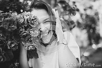 Beautiful black and white portrait of sensual brunette young woman in white dress close to red roses. Stock Photo