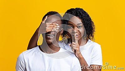 Beautiful black woman covering man eyes, showing silence gesture Stock Photo