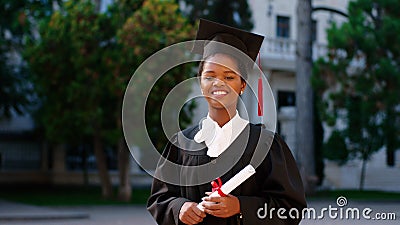 Beautiful black woman graduate posing with her diploma in front of the camera on the college garden she wearing Stock Photo