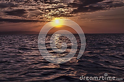 Beautiful blazing sunset landscape at Caspian sea and orange sky above it with awesome sun golden reflection on calm waves as a ba Stock Photo