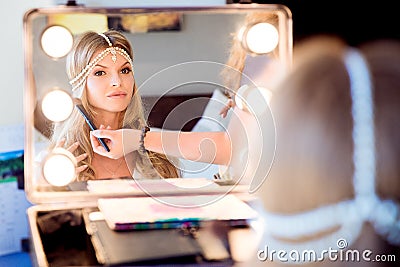 Beautiful blond bride doing makeup in her wedding day near mirror. Bride makeup. Stock Photo