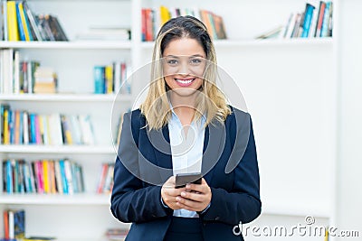 Beautiful blond businesswoman with tracing app at mobile phone Stock Photo