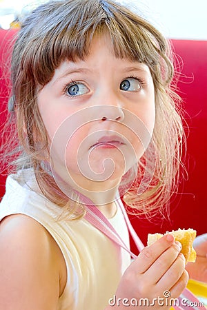Beautiful blond little dizzy concerned that called and reprimanded while chewing a piece of cake at a birthday party. Stock Photo