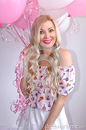 Beautiful blond woman with pink and white balloons. Joyful emotions. Celebration. Stock Photo