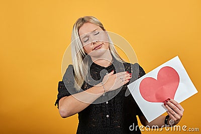 Girl in black dress disappointed sad woman holding piece of paper with red heart Stock Photo